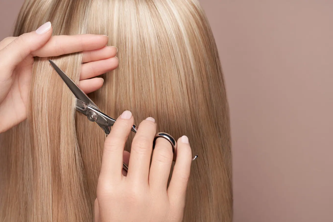 Taglio con le forbici su capelli lunghi biondi